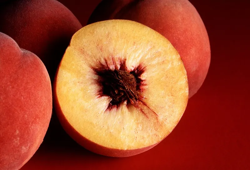 A peach, whole and halved to show the pit